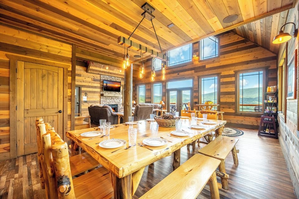 Gather around the handcrafted log dining table beneath vaulted wood ceilings, where rustic charm meets mountain elegance. Floor-to-ceiling windows frame breathtaking views and flood the space with natural light.