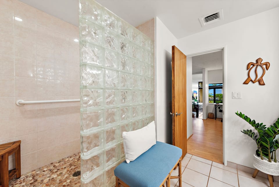 Your spacious walk-in shower features natural light through a decorative glass block wall, creating a warm, inviting atmosphere perfect for refreshing after a beach day.