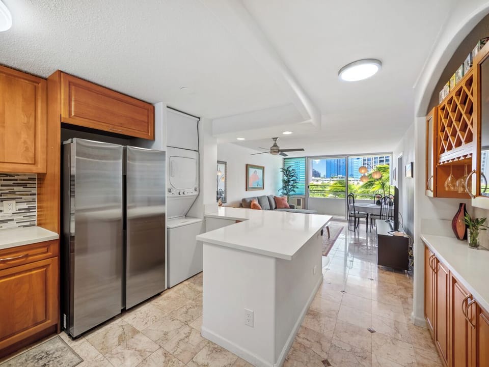 Living Room - Enjoy an easy open layout connecting the full kitchen, breakfast bar, living room, dining space, and private lanai/balcony, with in-unit laundry close at hand for a relaxed Waikiki monthly stay.