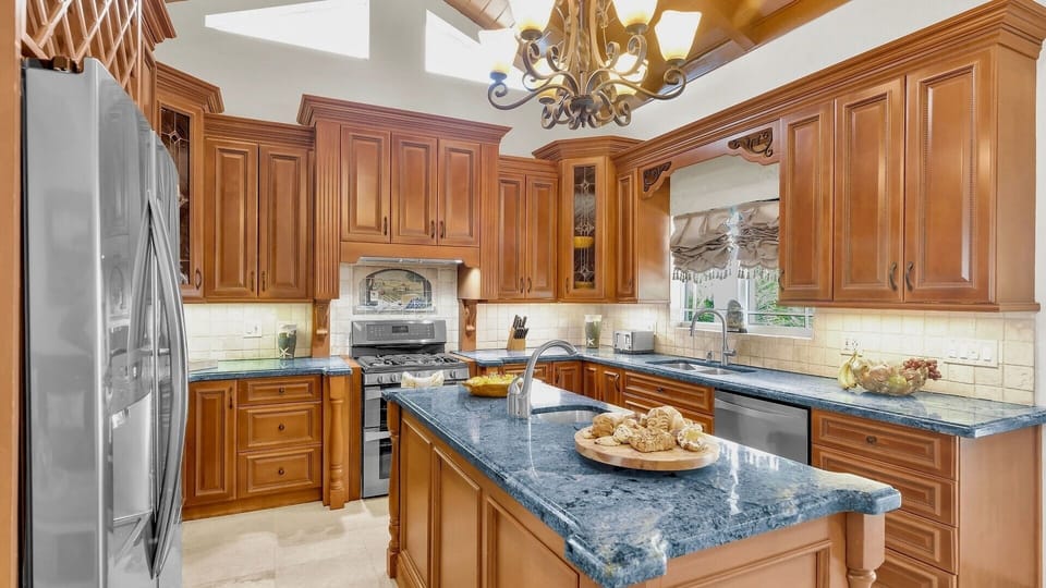 Rich wood cabinetry and a statement chandelier create a kitchen full of timeless charm...