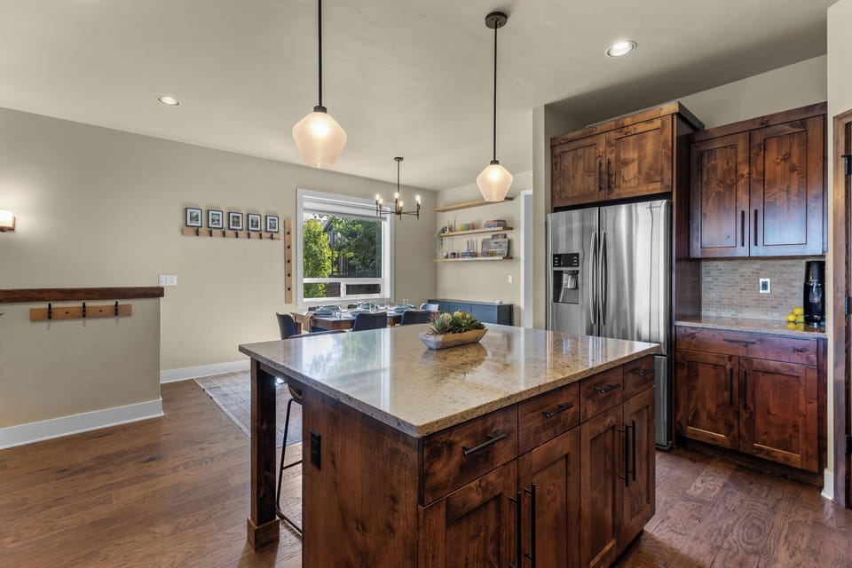 Step into your fully-equipped kitchen featuring warm wood cabinetry, a spacious island with bar seating, and stainless appliances—everything you need to prepare delicious meals at home.