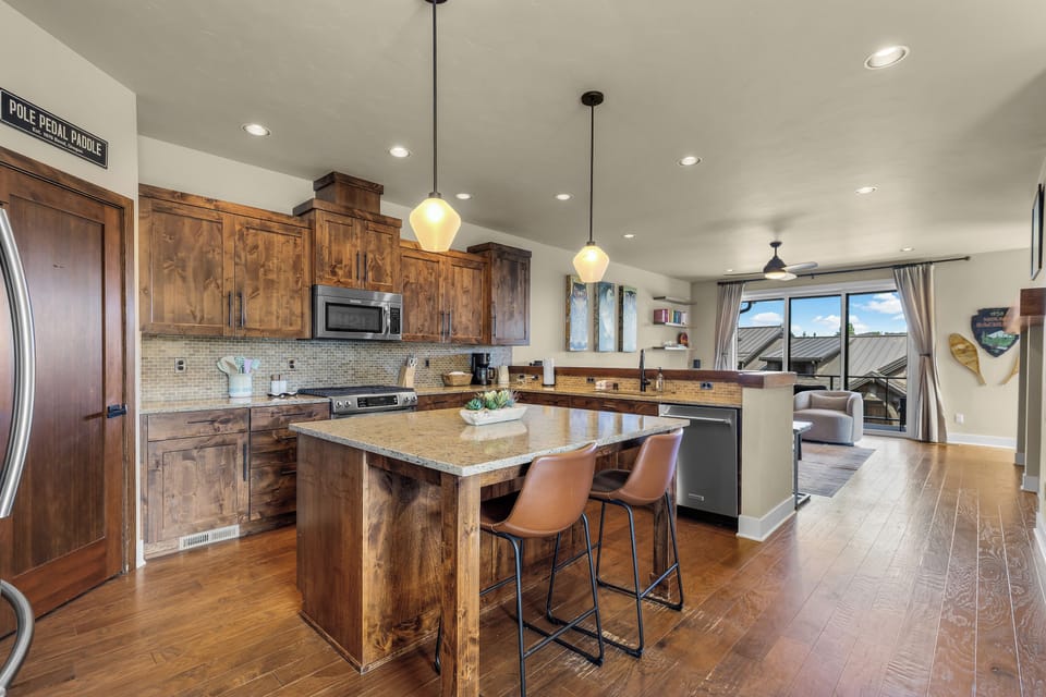 Your open-concept kitchen invites you to cook and gather with rich wood cabinets, granite counters, and modern appliances flowing into a bright, welcoming living space.