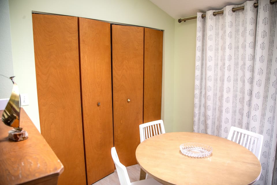 A spacious wardrobe for your belongings sits beside a charming round dining table, giving you a cozy spot to enjoy meals and unwind.