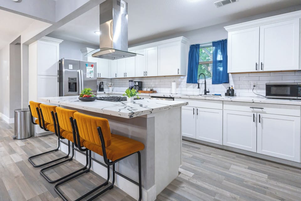 Bright contemporary kitchen featuring a spacious island, gas cooktop, stainless steel appliances, and ample counter space for cooking and gathering.