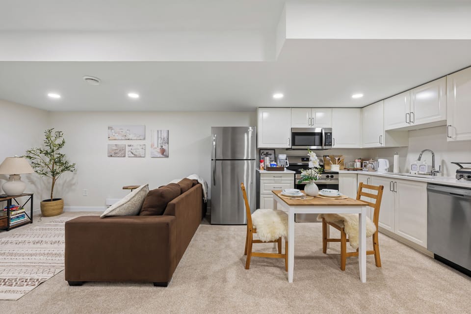 Bright open living space with Smart TV, cozy sofa, dining nook, and full kitchen