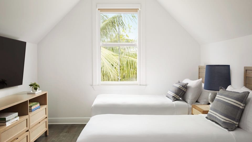Recharge in airy twin beds beneath calming tropical light.