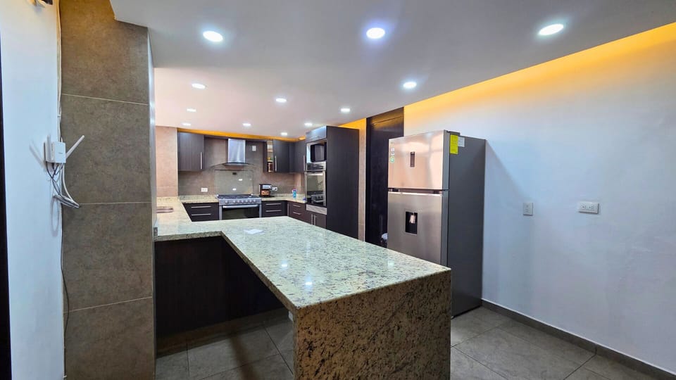Modern kitchen with granite island, stainless appliances, and sleek lighting