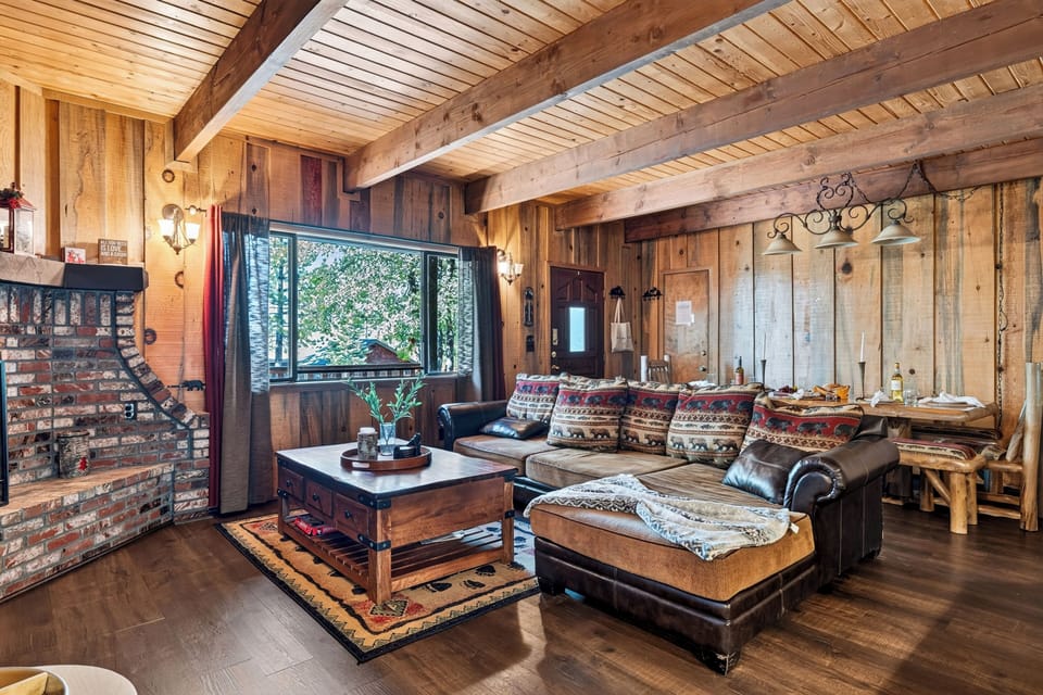 Spacious open-concept living area showcasing rich wood tones, a large comfortable sectional, and a cozy cabin ambiance.