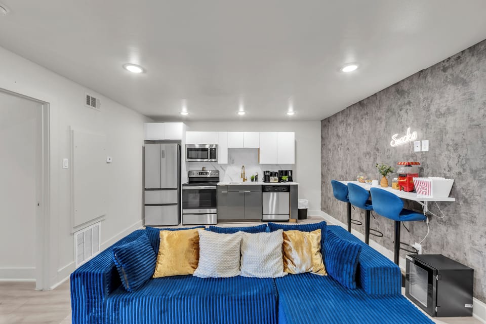 Modern studio living with bold blue sofa, sleek kitchen, and chic dining nook
