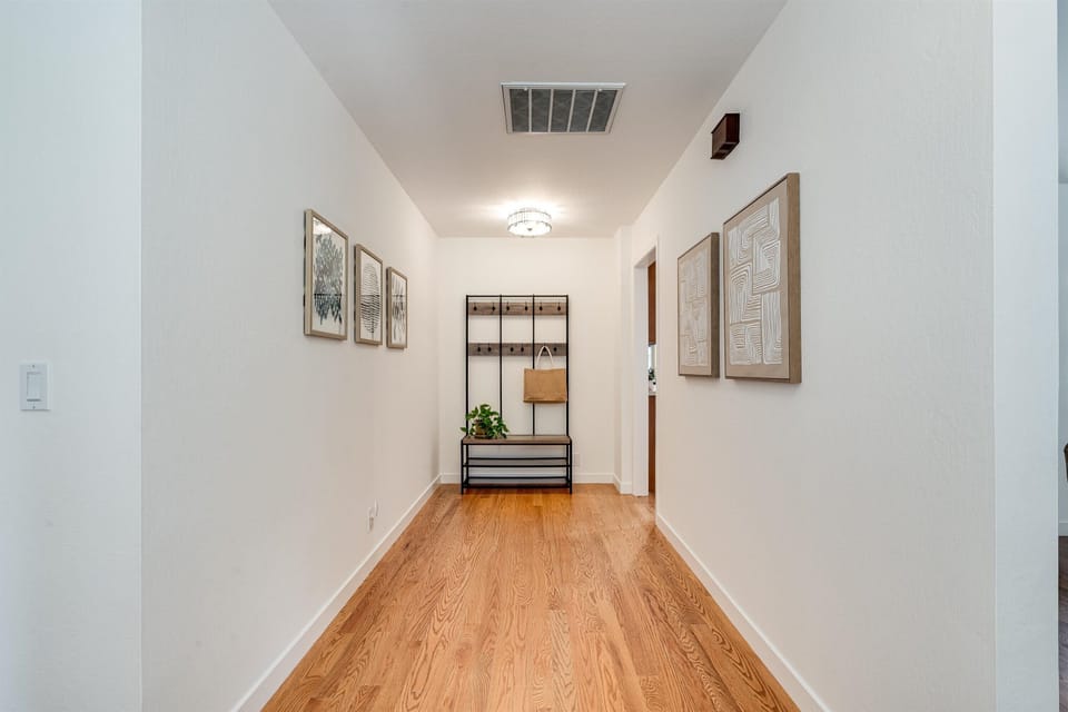 Step into your welcoming hallway, where warm wood floors guide you through this thoughtfully designed space. Crisp white walls and calming artwork set a relaxing tone the moment you arrive.