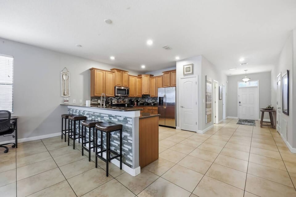 Spacious open kitchen with breakfast bar, stainless appliances, and bright entry