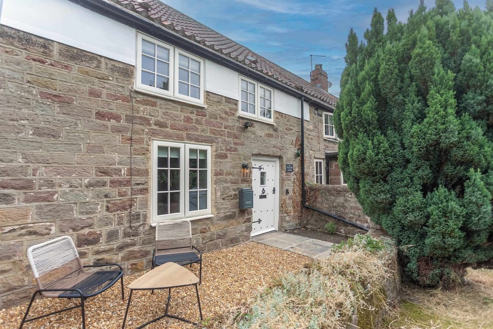 Step outside with your morning coffee and enjoy the cottage setting, where traditional stonework and a peaceful seating area invite you to pause awhile.