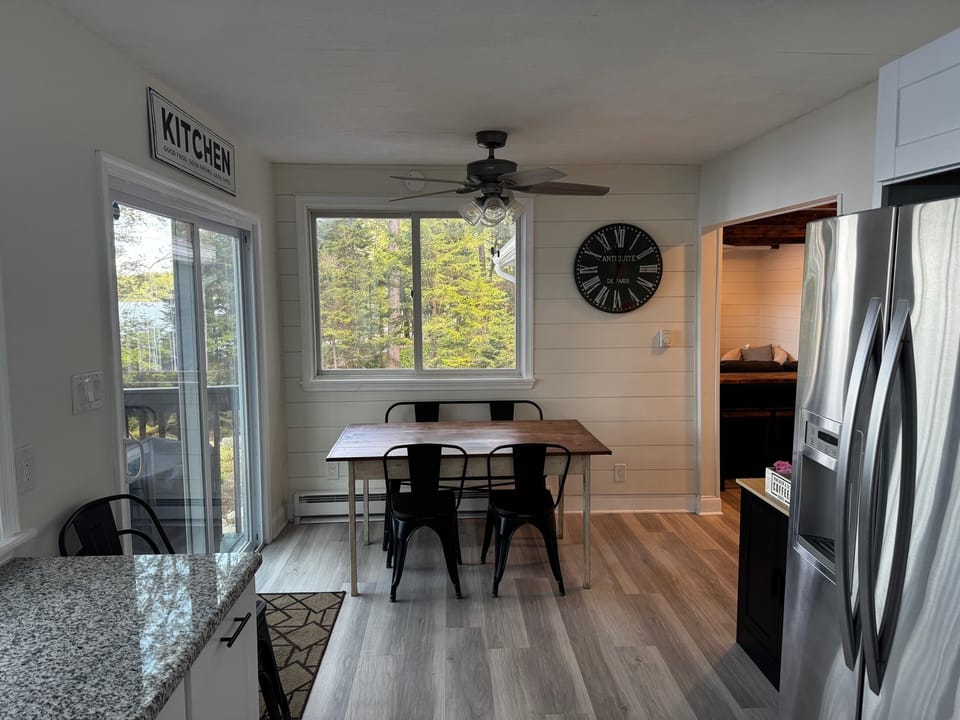 Bright dining area with lake views, rustic wood table, and  farmhouse character.