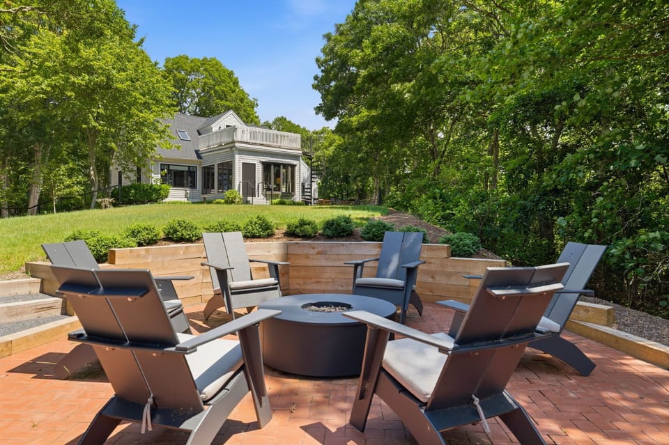 Private backyard fire pit patio surrounded by lush trees