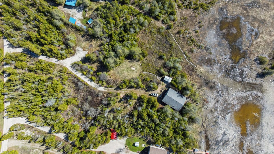An aerial view showcasing the private cottage setting, surrounded by trees and just moments from the shoreline.