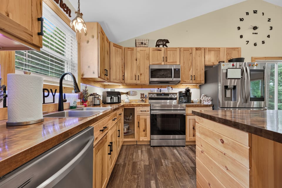 A rustic kitchen featuring light wood cabinetry and stainless steel appliances.