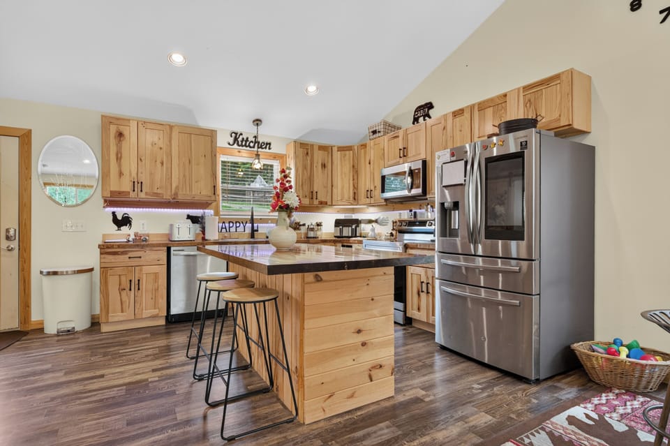 A rustic kitchen featuring wooden cabinetry, a central island with bar stools.