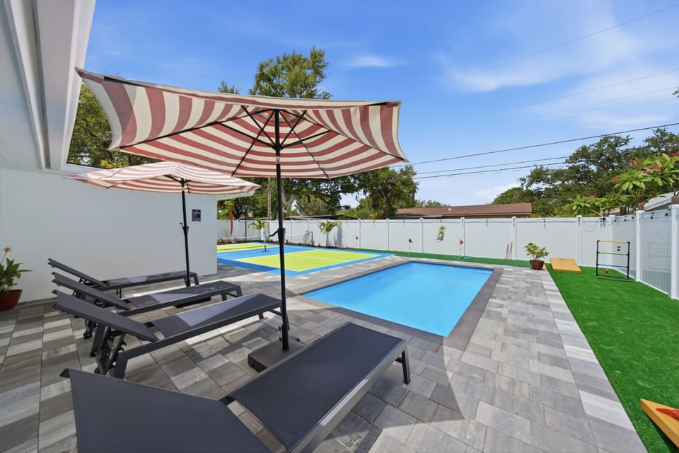 Private pool patio with loungers, umbrellas, and a fun sport court