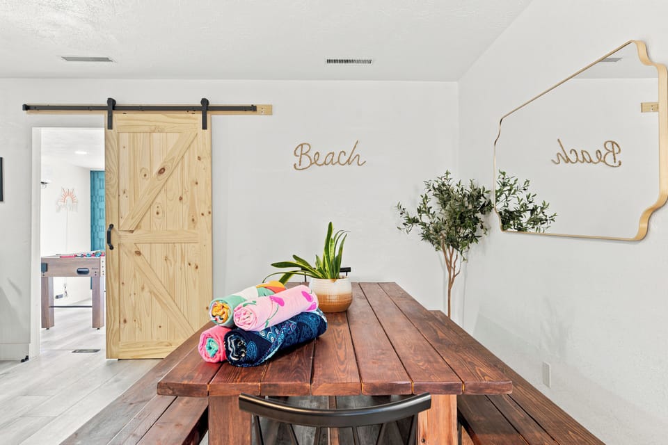 Bright beach-themed dining space with rustic table and stylish barn door
