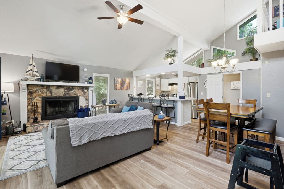 Bright open living area with vaulted ceilings and cozy stone fireplace