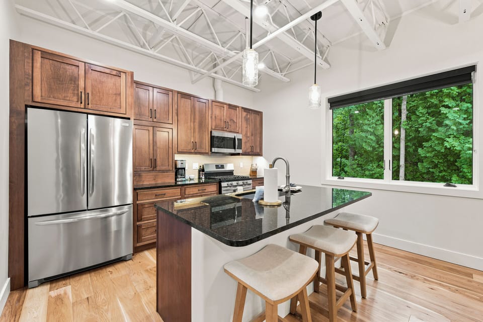 Modern kitchen with sleek island seating and peaceful forest views.
