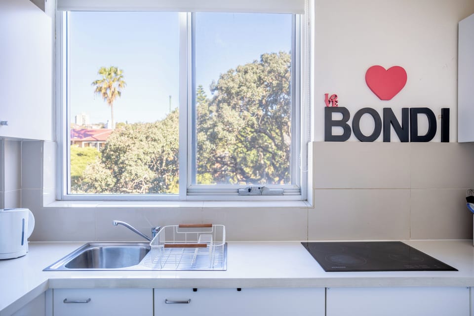 Kitchen sink and stovetop with leafy window view