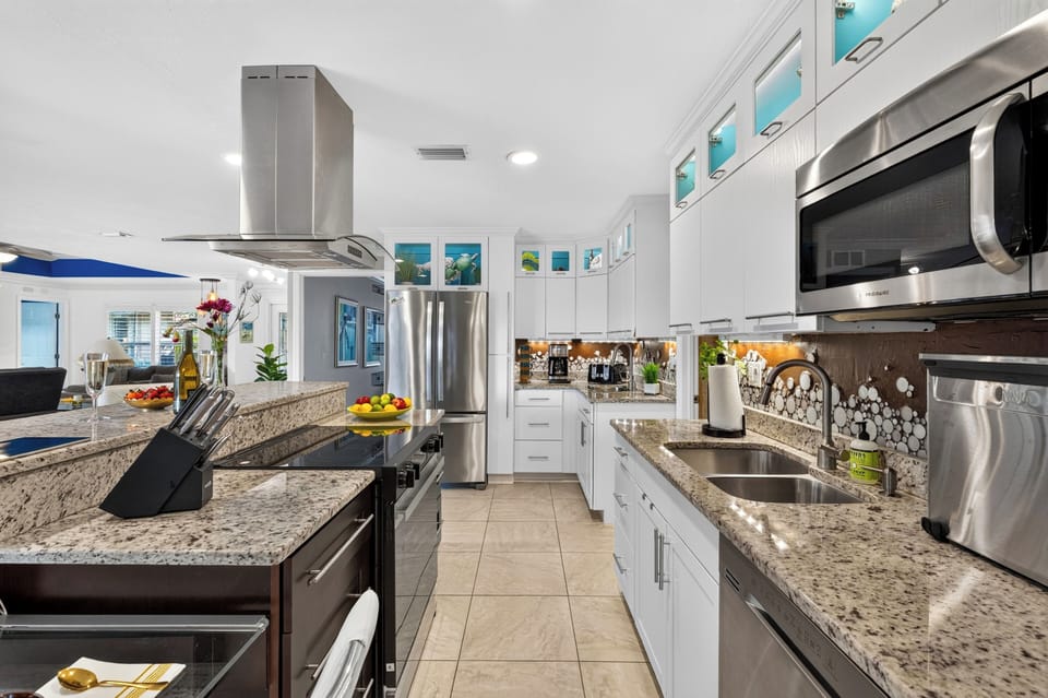 Modern kitchen with a spacious island, bar seating, and open flow into the family and living rooms.
