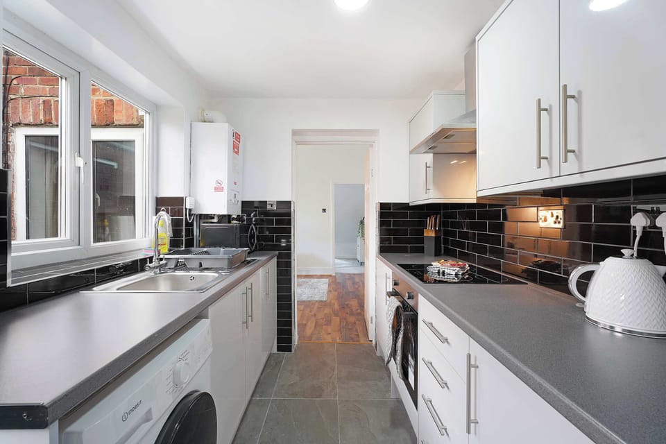 Prepare meals with ease in the modern kitchen featuring an oven, hob, microwave, fridge, freezer, washing machine, kettle, toaster, and sink. Complete with cookware, utensils, mugs, glassware, and cleaning supplies.