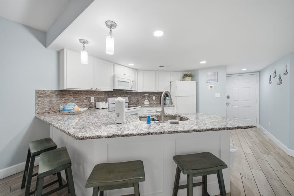 Kitchen island with granite counters and barstool seating for three