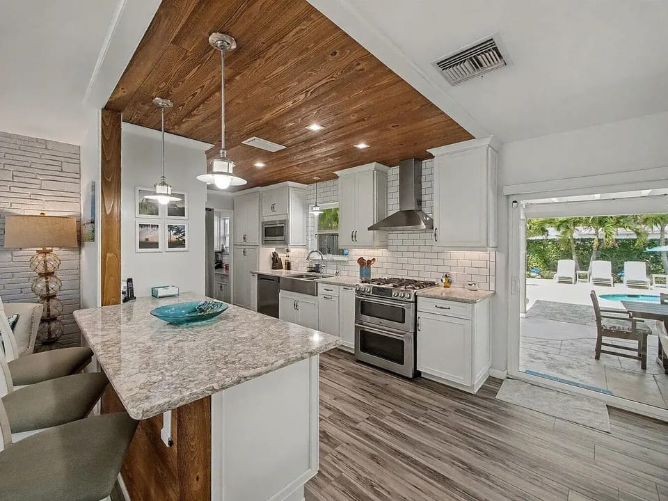 The heart of the home, combining a warm wooden ceiling detail with a sleek, fully stocked cooking setup.
