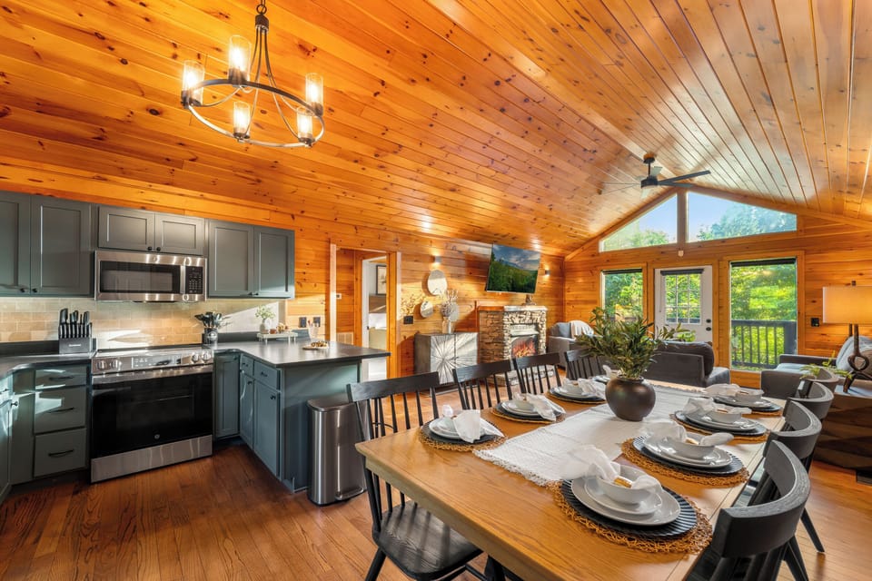 Warm cabin great room with chef’s kitchen, fireplace, and scenic windows
