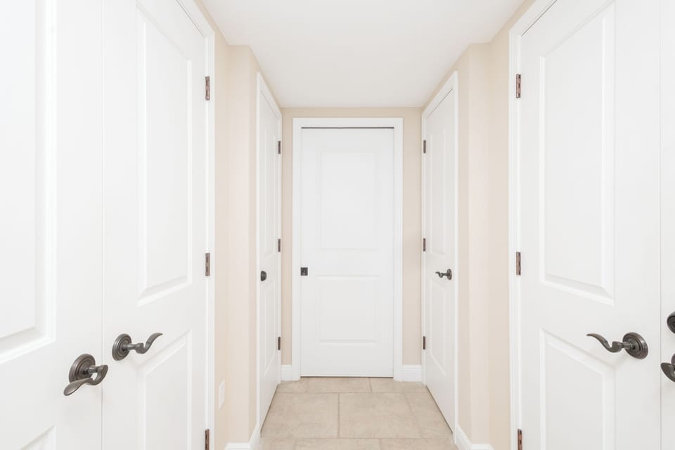 A bright, welcoming hallway with elegant details leads to your private spaces, with multiple doors opening to the comforts that await you inside.