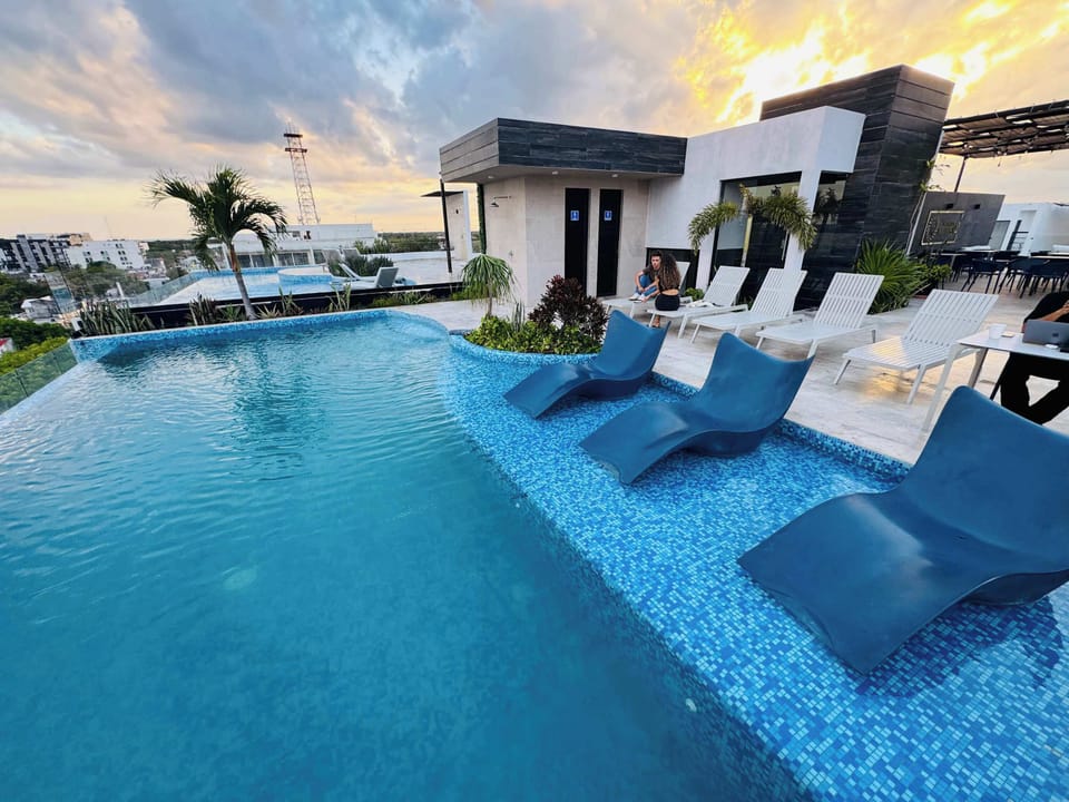 Rooftop pool with loungers bathed in golden light, unwind as the day fades over Playa
