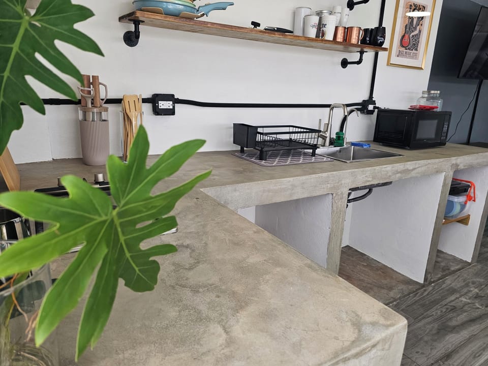 Modern kitchenette with concrete counters and sleek open shelving
