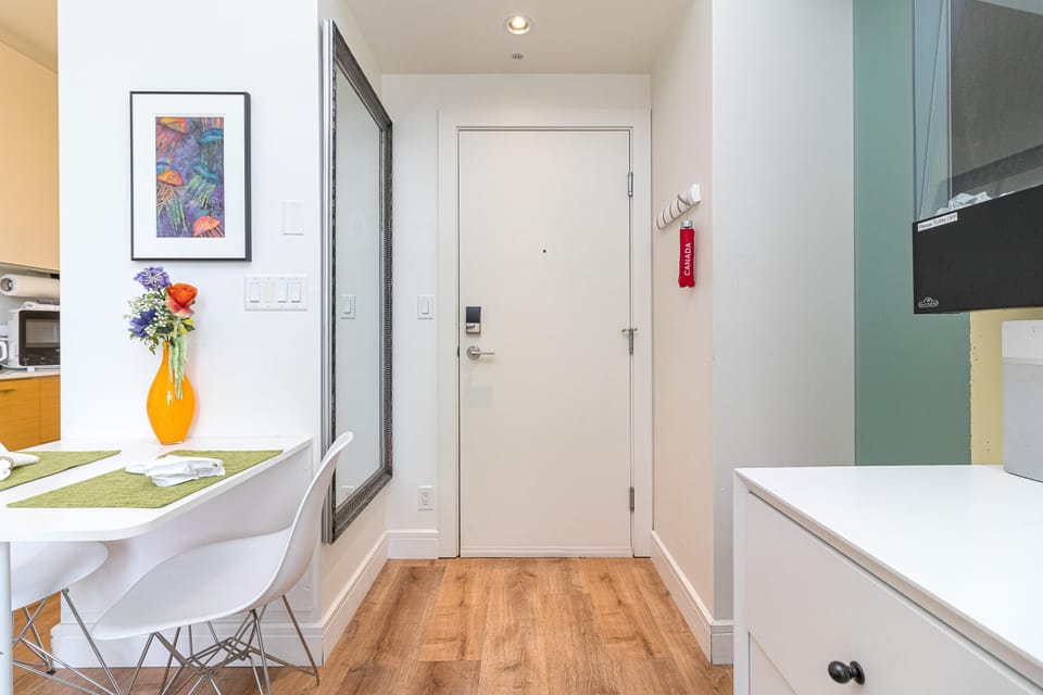 Entryway with wood-look flooring, a tall silver-framed mirror, and a white door with electronic lock.