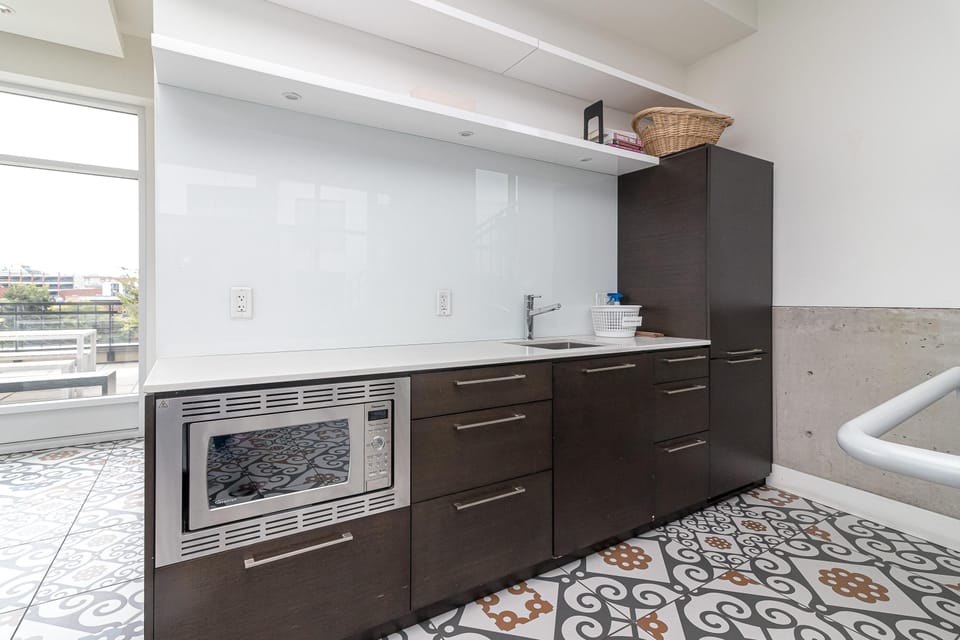 The resident community lounge features a convenient shared kitchen prep area with modern cabinetry and sink.