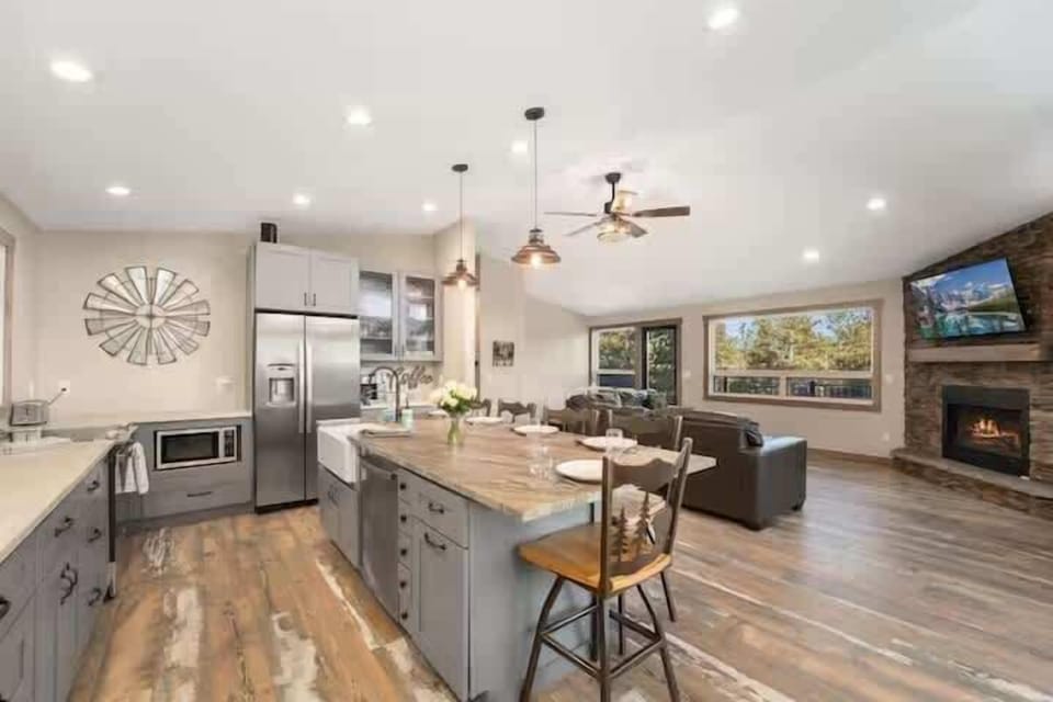 Kitchen and living area with open layout, fireplace, and wooded views