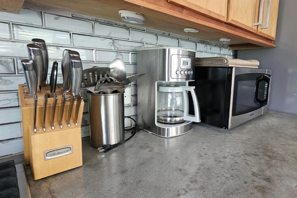 Well-stocked kitchen counter with coffee maker, microwave, and prep essentials