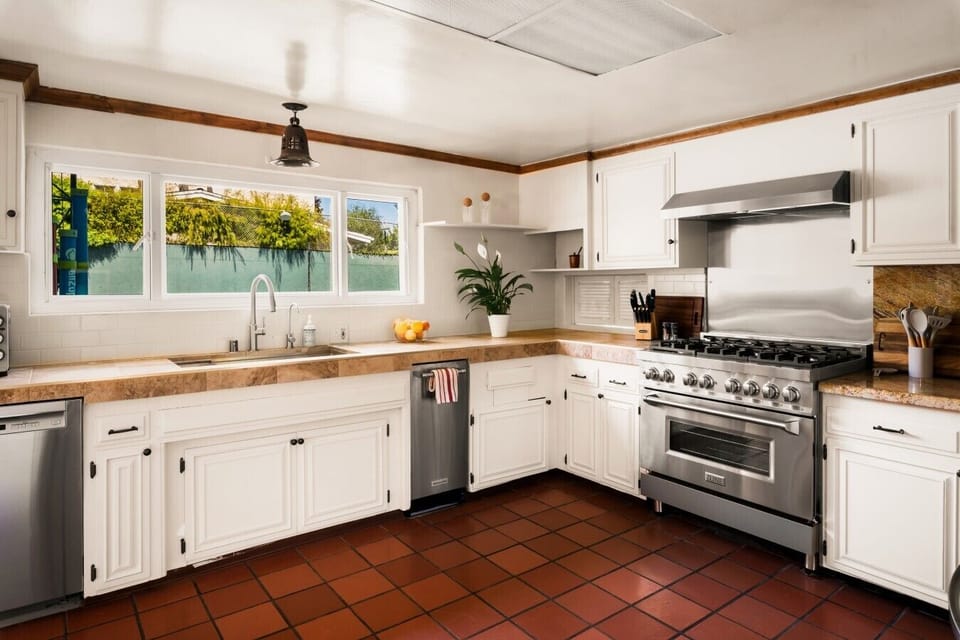 Sunny kitchen with garden window and terracotta tile floors