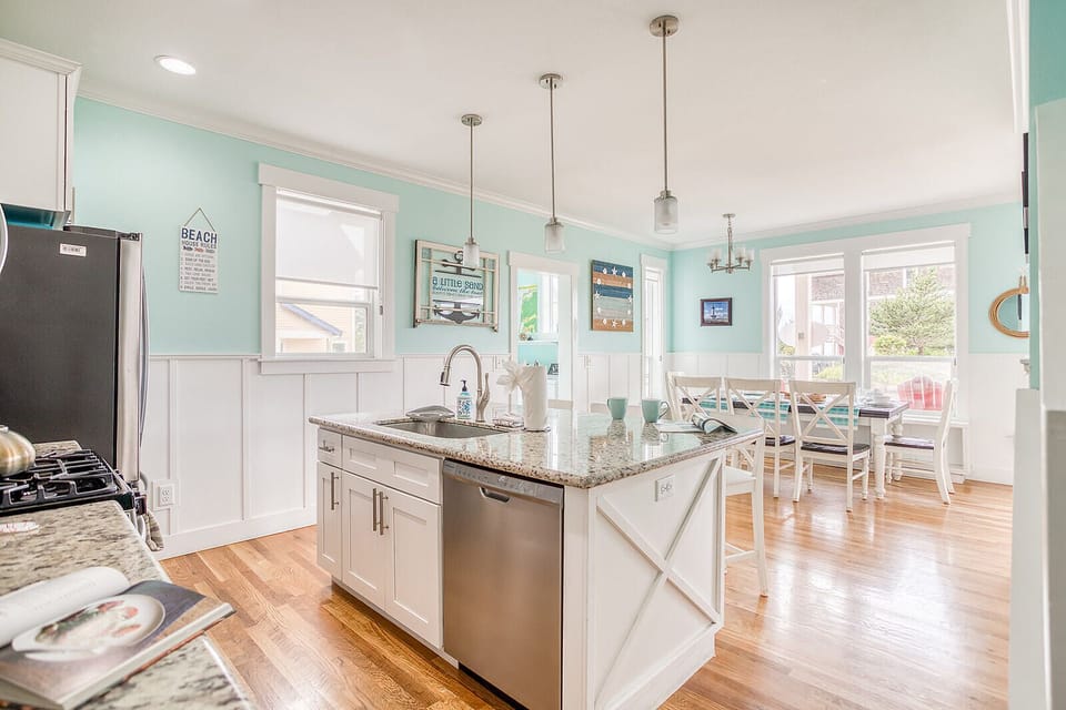 Gather around the island in your bright coastal-inspired kitchen, where sunlight streams through large windows and beachy decor sets a relaxing, vacation-ready tone for meals and memories.