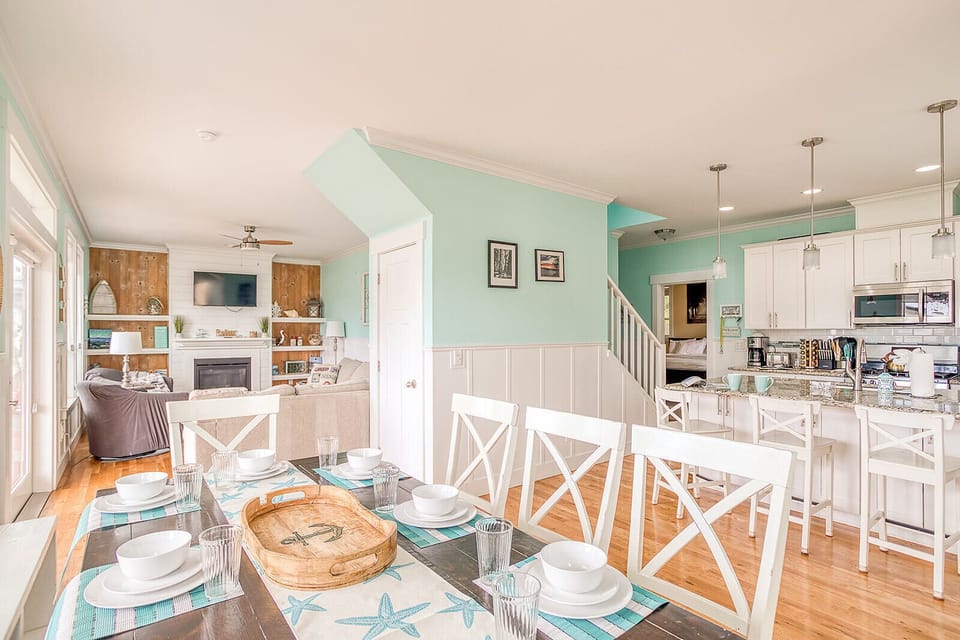 Bright open living space features coastal-inspired décor with modern kitchen, cozy dining for eight, and inviting living room—perfect for gathering together.