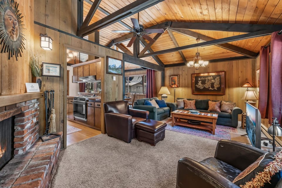 Unwind in your spacious living area with soaring wood-beamed ceilings, a cozy fireplace, and plush leather seating—a perfect retreat after a day of mountain adventures.