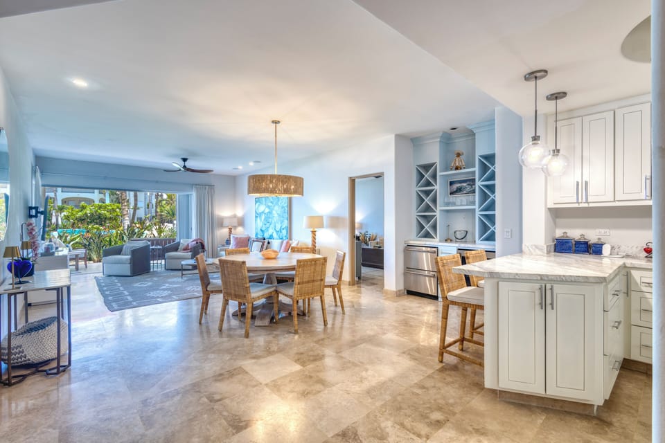 Step into this bright, open-concept space where your kitchen flows into a welcoming dining and living area. Sun-drenched windows frame lush tropical views, inviting you to unwind in comfort and style.