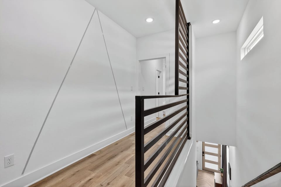 Bright modern landing with sleek railing and warm wood floors.