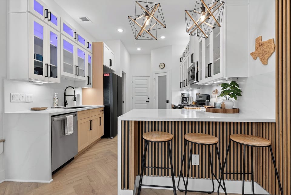 Sleek chef’s kitchen with quartz island, LED-lit cabinets & bar seating.