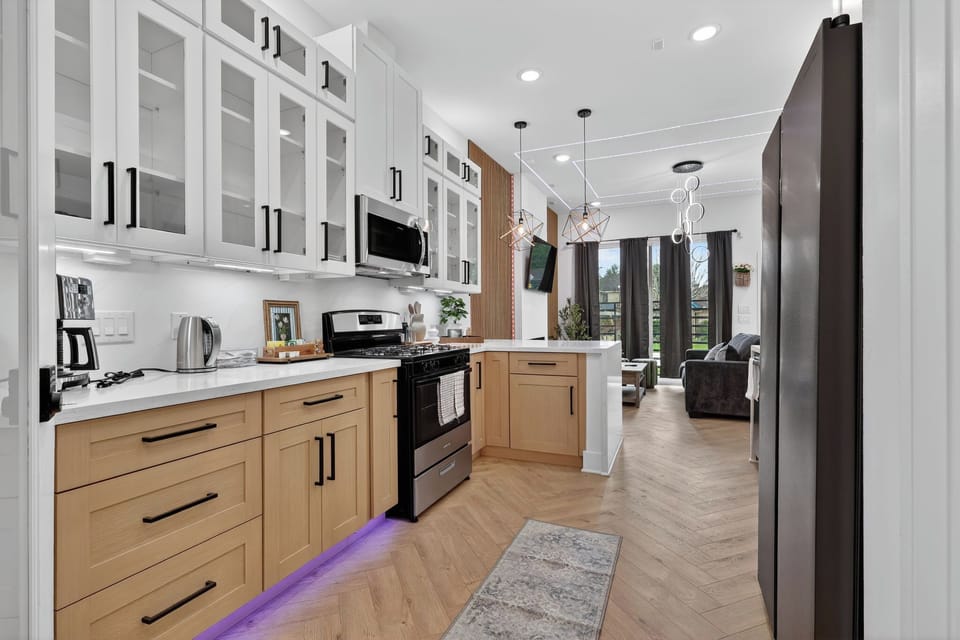 Stylish two-tone kitchen with LED accents, open to bright lounge