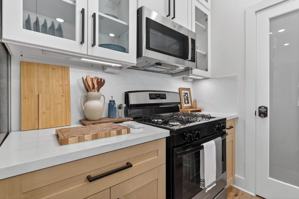 Modern kitchen with gas range, quartz counters & glass cabinets