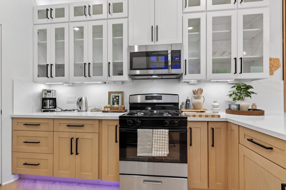 Stylish two-tone kitchen with gas range, glass uppers & coffee bar.