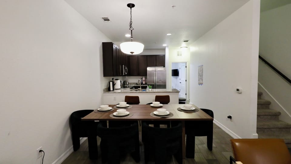 Open dining area with set table, breakfast bar, and modern kitchen