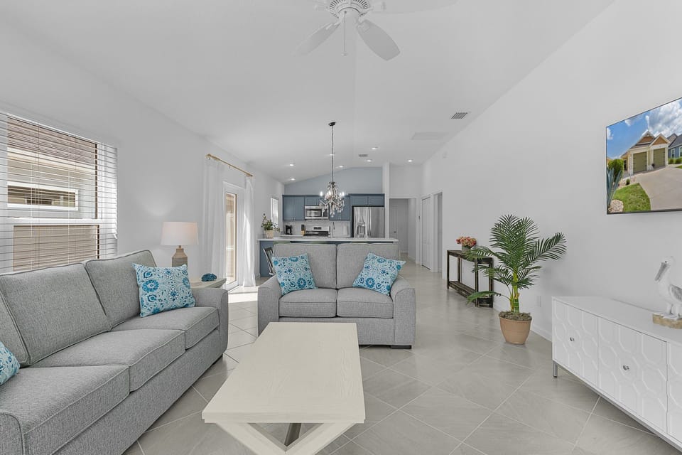 Unwind in your bright, open living area with plush sofas, soothing blue accents, and a fully equipped kitchen just steps away—perfect for your home-away-from-home getaway.